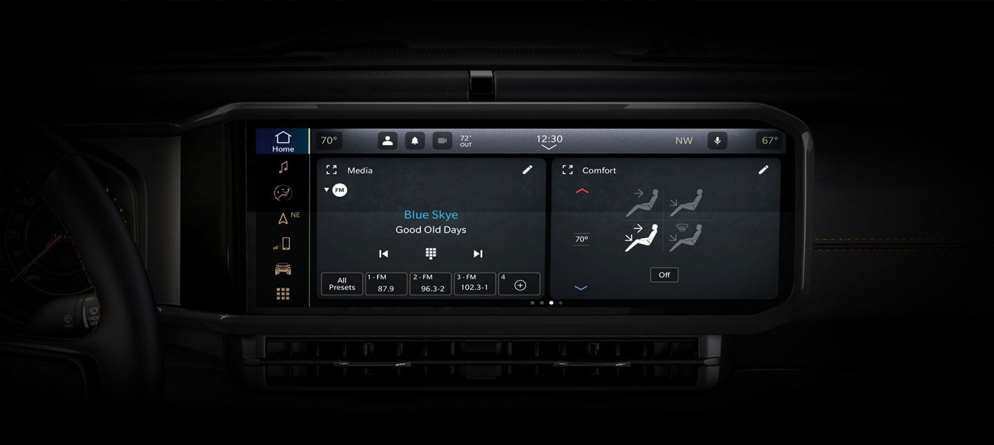 A close-up of the Uconnect 5 Nav touchscreen in the 2024 Jeep Wrangler with a split-screen displaying the radio selection and climate controls.